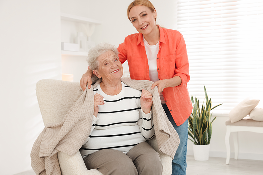 Caregiver covering senior woman with blanket