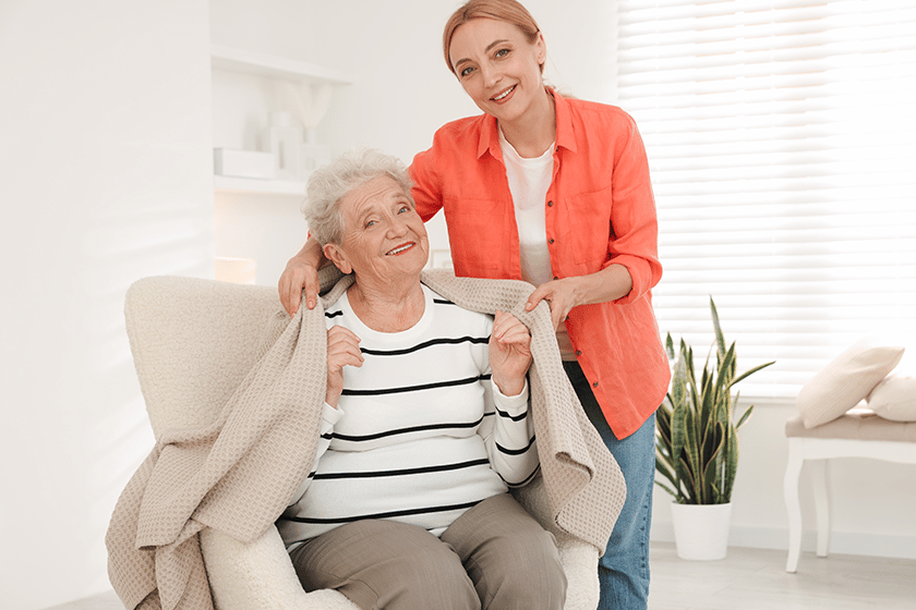 Caregiver covering senior woman with blanket